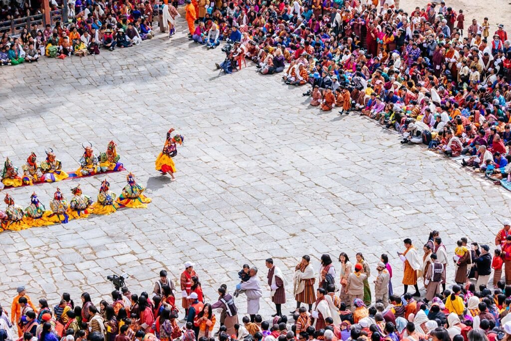 spectators in colorful clothing watch the dance performers at the paro festival
