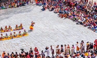 spectators in colorful clothing watch the dance performers at the paro festival